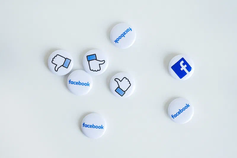 Traditional pin-back buttons with Facebook icons on them resting against a white background.