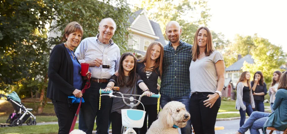 A smiling family sitting together outdoors with their dog